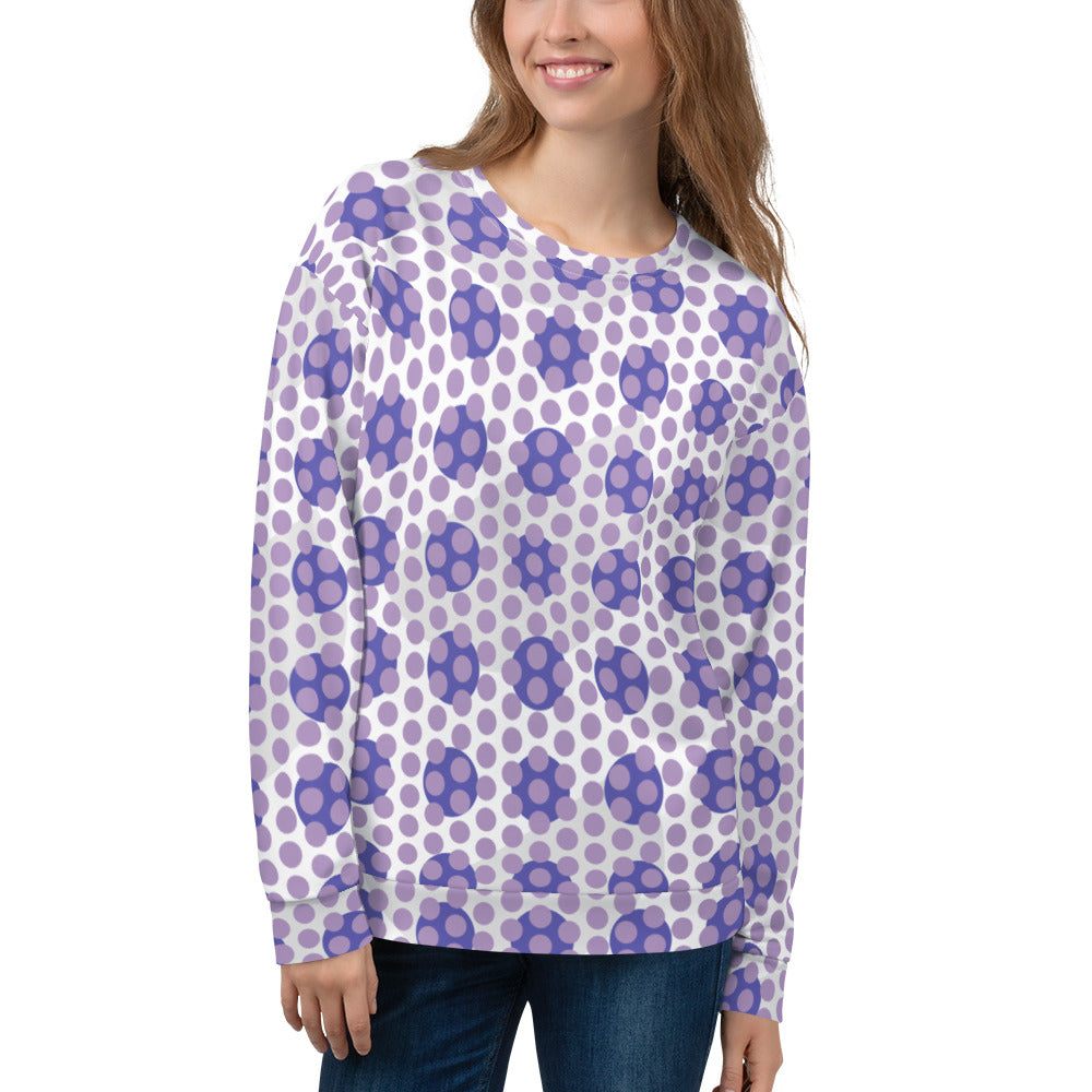 A woman smiling, wearing a unisex recycled polyester sweatshirt with a colorful all-over polka-dot pattern.