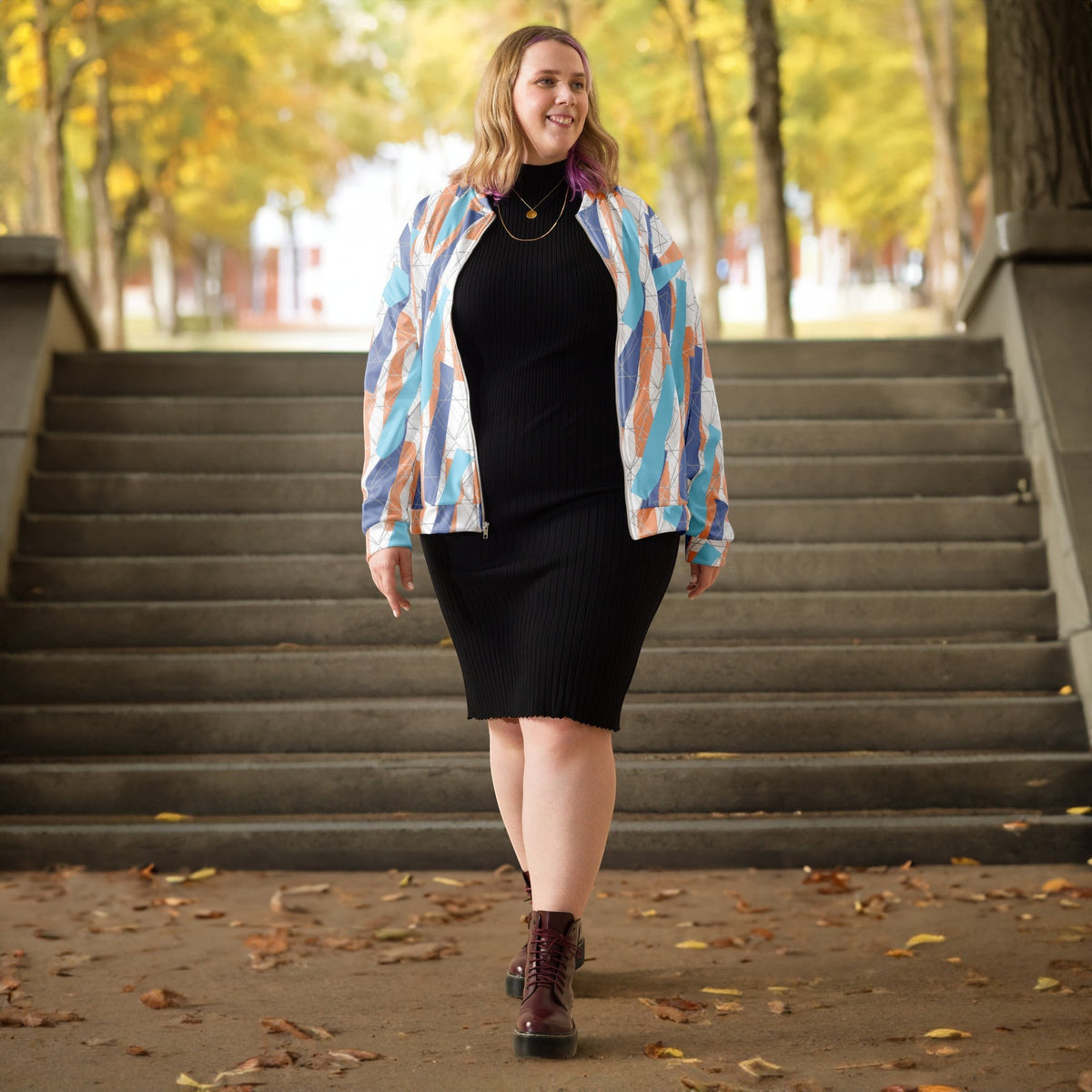 Good Wishes 365 unisex bomber jacket with abstract orange and blue print worn by a woman over a black ribbed dress