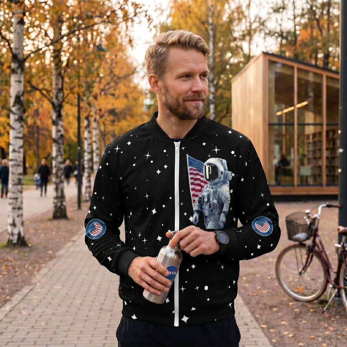 Good Wishes 365 black bomber jacket with astronaut and moon landing print worn by a man in an autumn park