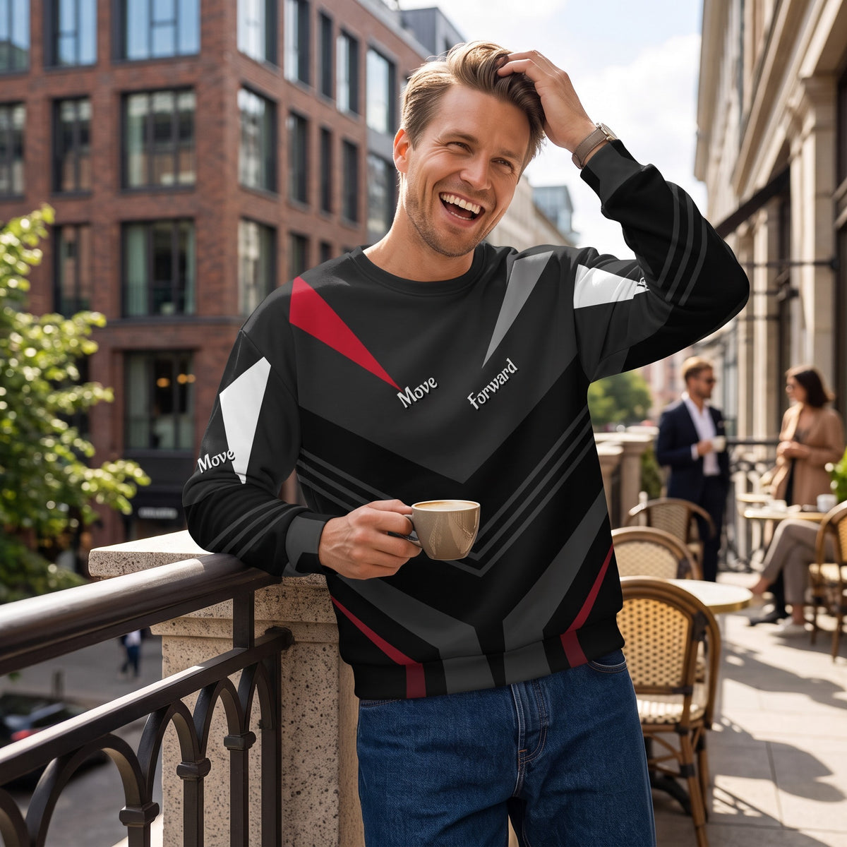 Good Wishes 365 black recycled sweatshirt with red and grey V-line athletic print worn by a smiling man on a balcony