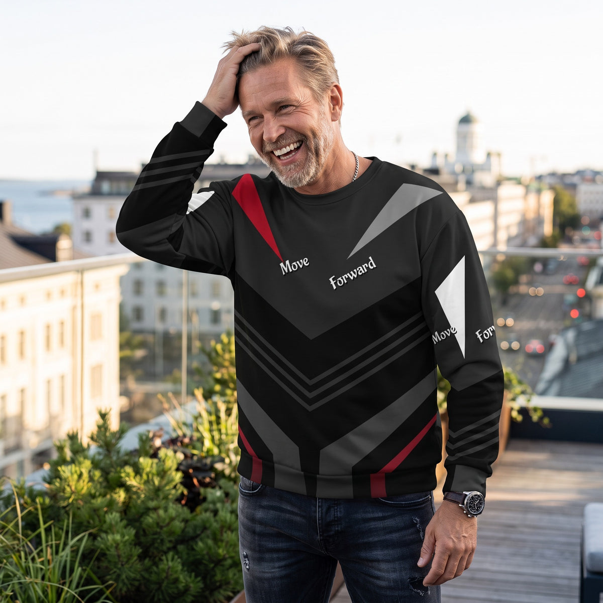Good Wishes 365 black recycled sweatshirt with red and grey V-line pattern worn by a smiling man on a city rooftop