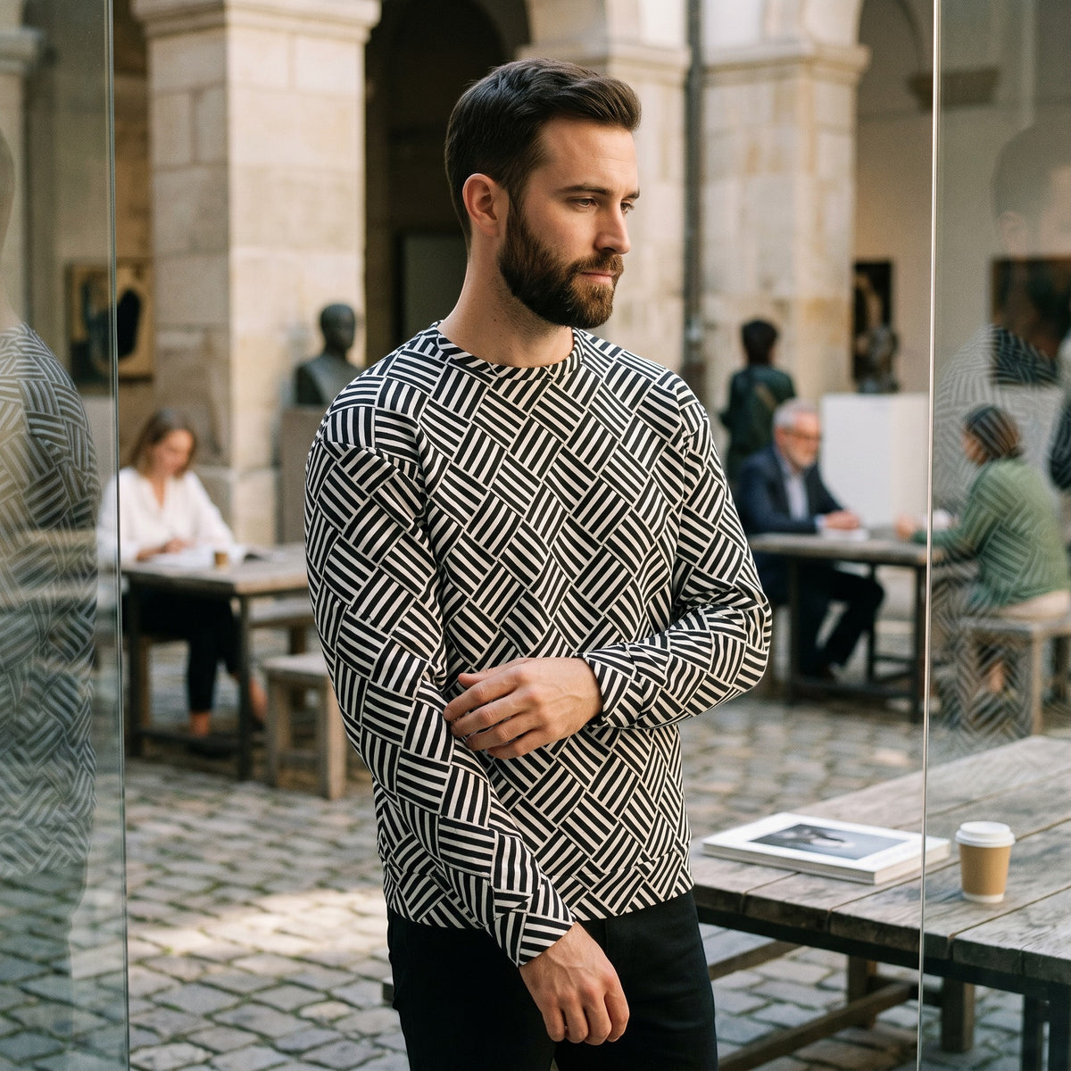 Good Wishes 365 unisex sweatshirt with a black and white geometric basketweave pattern worn by a man in a courtyard.