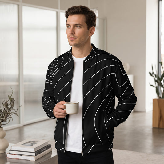 Good Wishes 365 black bomber jacket with white wave line print worn by a man holding a coffee mug in a bright room.