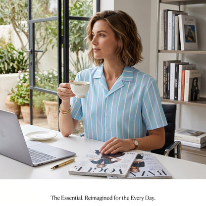 Good Wishes 365 light blue and white striped short sleeve button-up shirt with camp collar worn by a woman at a desk