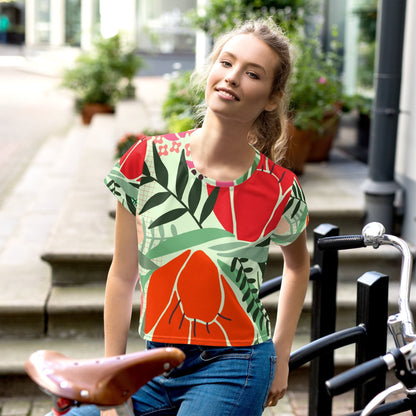 Good Wishes 365 crop tee with red and orange floral print on a mint green background, worn by a woman on a bike.