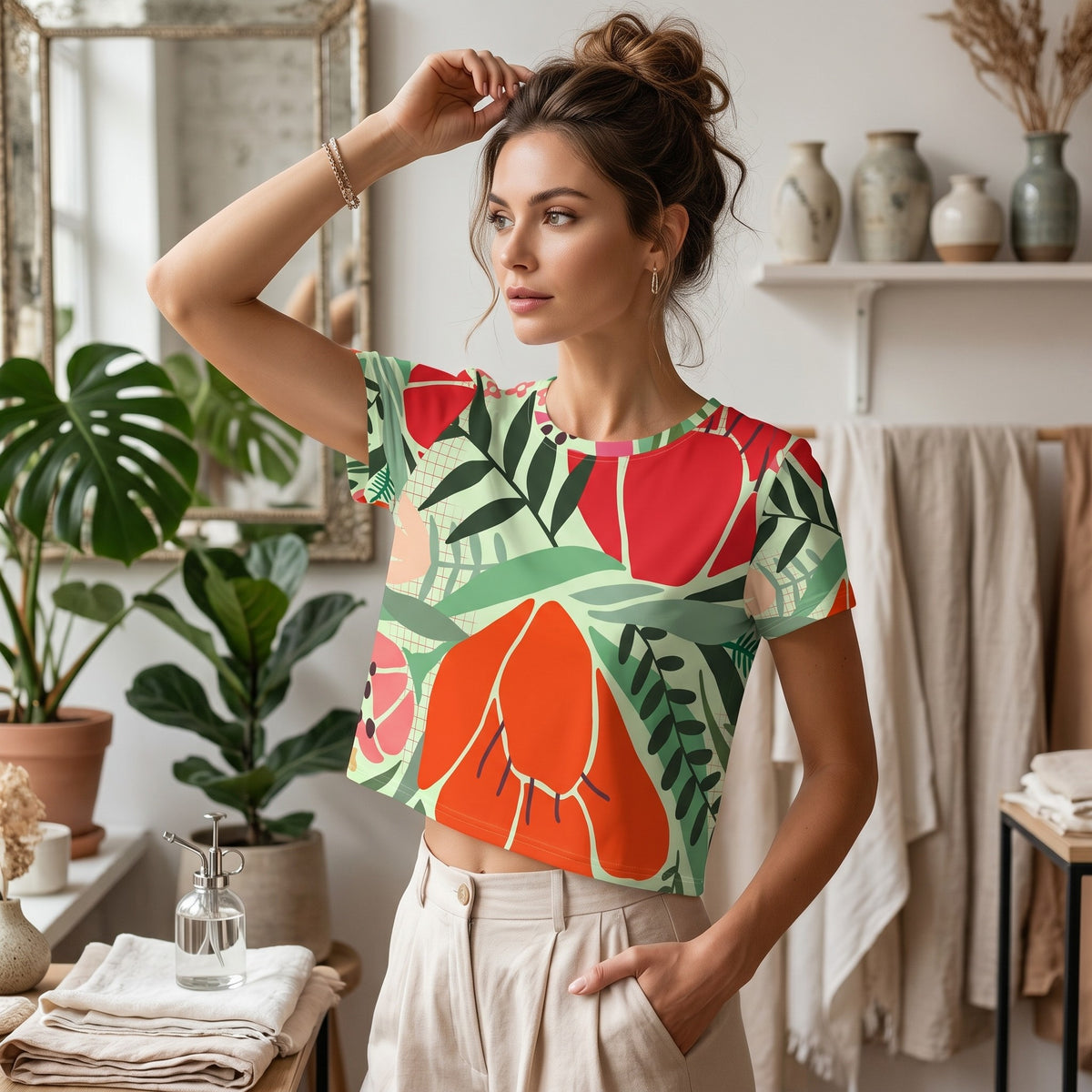 Good Wishes 365 mint crop tee with red and orange floral print, worn by a woman in a bright, plant-filled room.