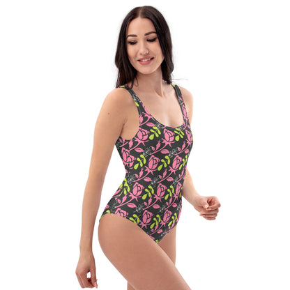 Good Wishes 365 one-piece swimsuit featuring a dark background with a vibrant pink rose and green leaf floral print.