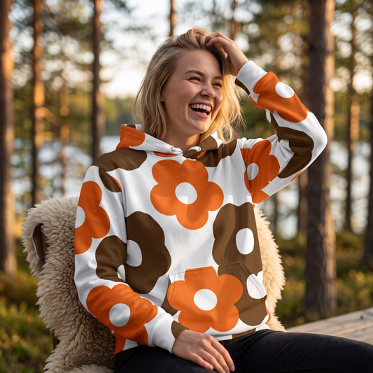 A smiling woman wearing a Good Wishes 365 recycled hoodie with a retro brown and orange floral print in a forest.
