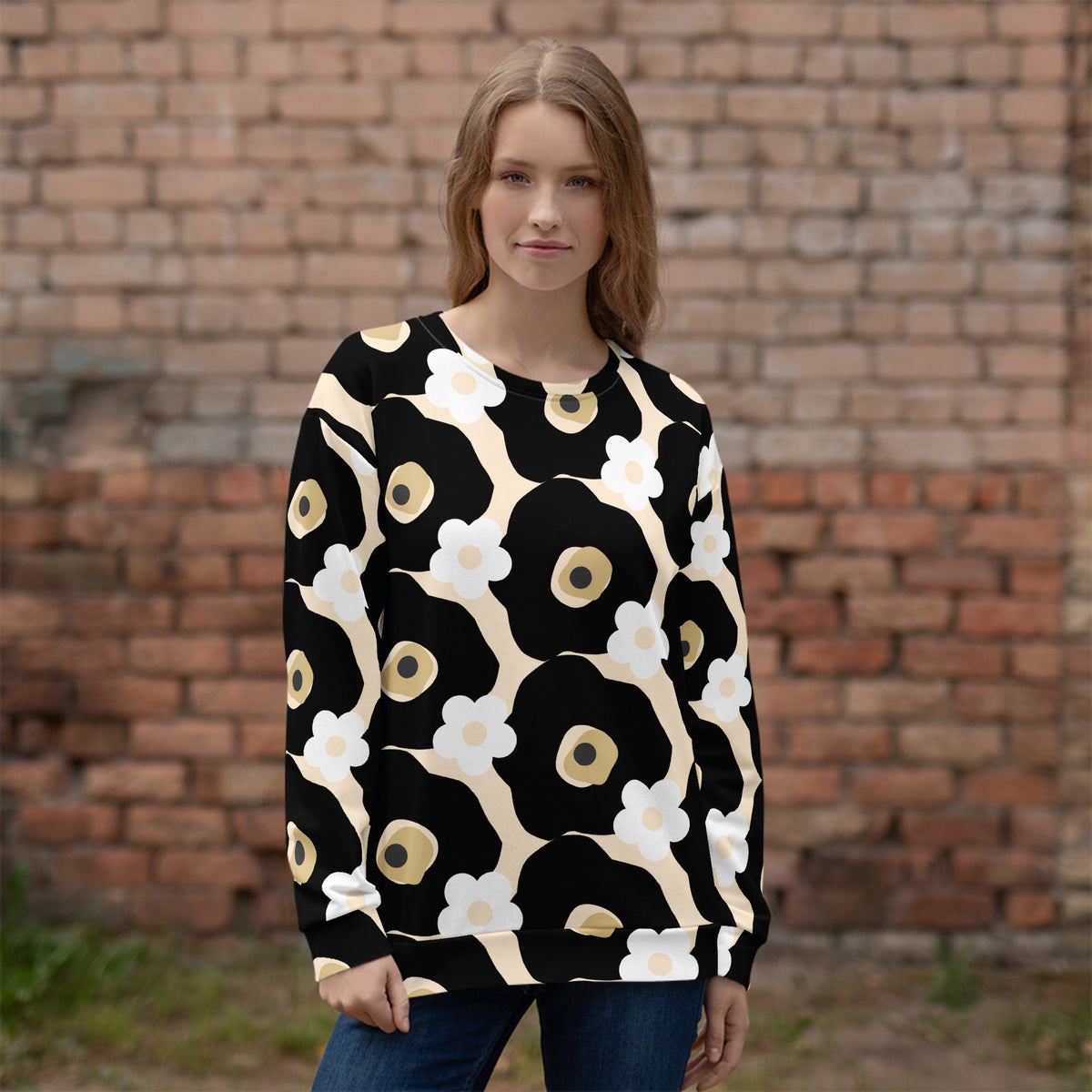 Good Wishes 365 recycled sweatshirt with black, white, and beige floral print worn by a woman against a brick wall.