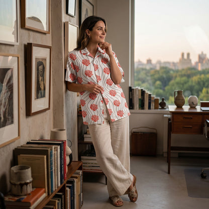 Good Wishes 365 unisex button-up shirt with red rose floral print and wavy lines, worn by a woman in a sunlit room.