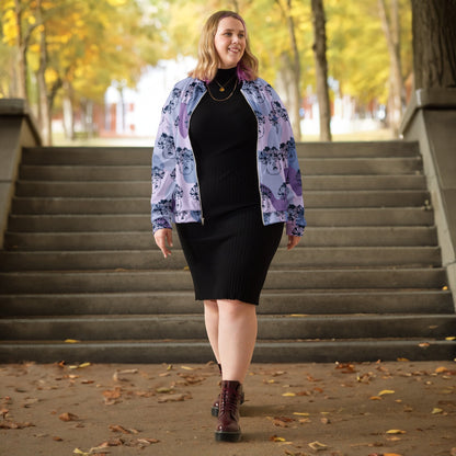Good Wishes 365 unisex bomber jacket with purple flowercrown print worn by a woman over a black ribbed dress outdoors.