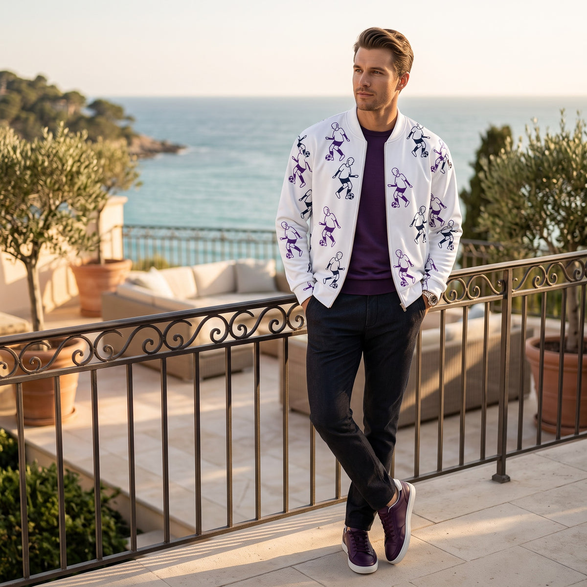Good Wishes 365 white bomber jacket with purple football player print, worn by a man on a sunny terrace.