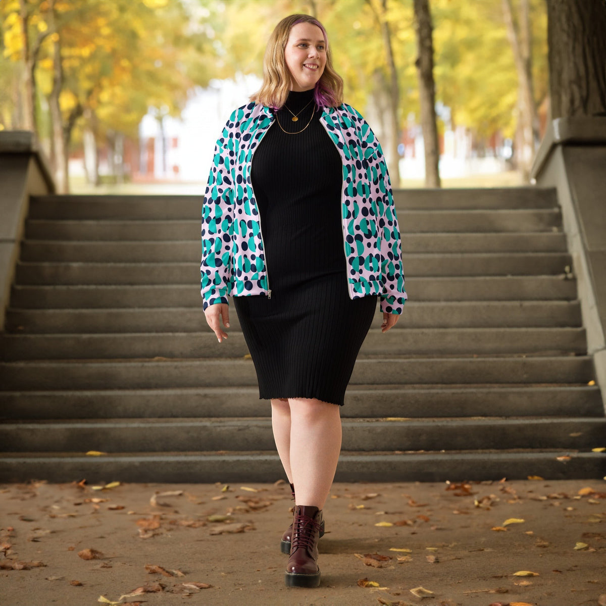 Good Wishes 365 bomber jacket with navy polka dots and blue semi-circles worn by a woman over a black ribbed dress