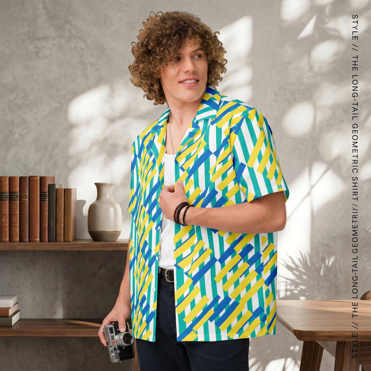 Good Wishes 365 unisex oversized button shirt with a yellow, blue, and green geometric pattern worn by a curly-haired man.