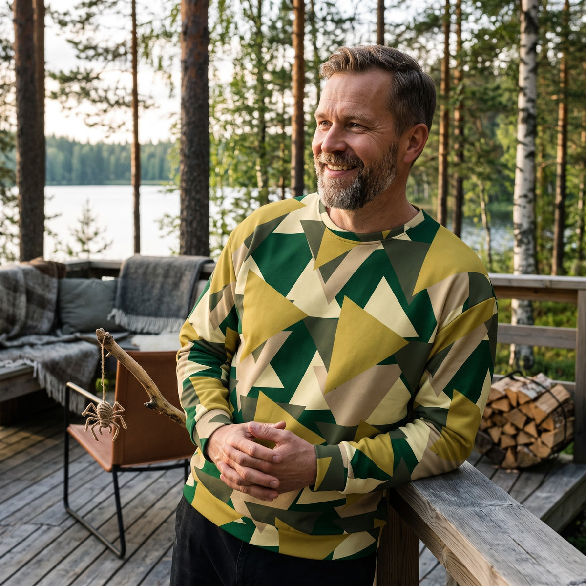 Good Wishes 365 men's recycled sweatshirt with a geometric camo print in green, olive, and beige on a wooden deck.