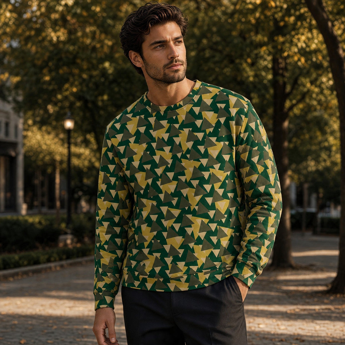A man wearing a Good Wishes 365 geometric camo print sweatshirt in forest green and yellow outdoors.