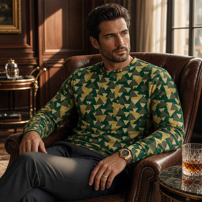 A man wearing a Good Wishes 365 geometric camo print sweatshirt in forest green and yellow, seated in a leather chair.