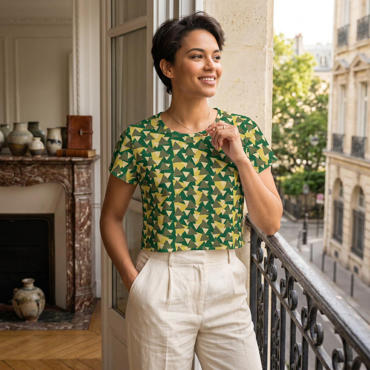 Good Wishes 365 woman wearing a green and yellow geometric camouflage print crop tee on a balcony