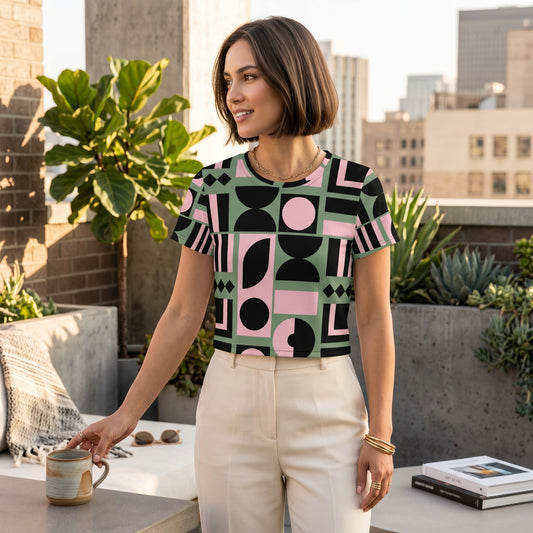 Good Wishes 365 crop tee with pink, green, and black geometric print worn by a woman on a sunny rooftop terrace.
