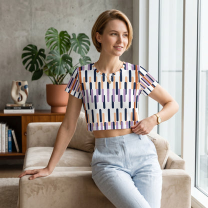 Good Wishes 365 crop tee with a purple, orange, and navy geometric print, worn by a woman in a bright living room.