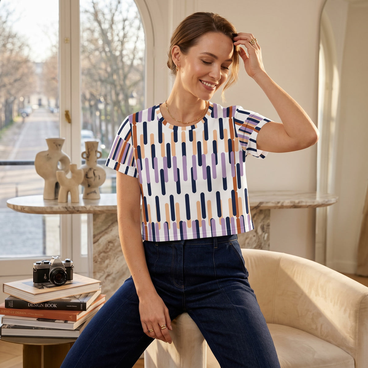 Good Wishes 365 woman wearing a white crop tee with a colorful geometric vertical stripe pattern in a bright room