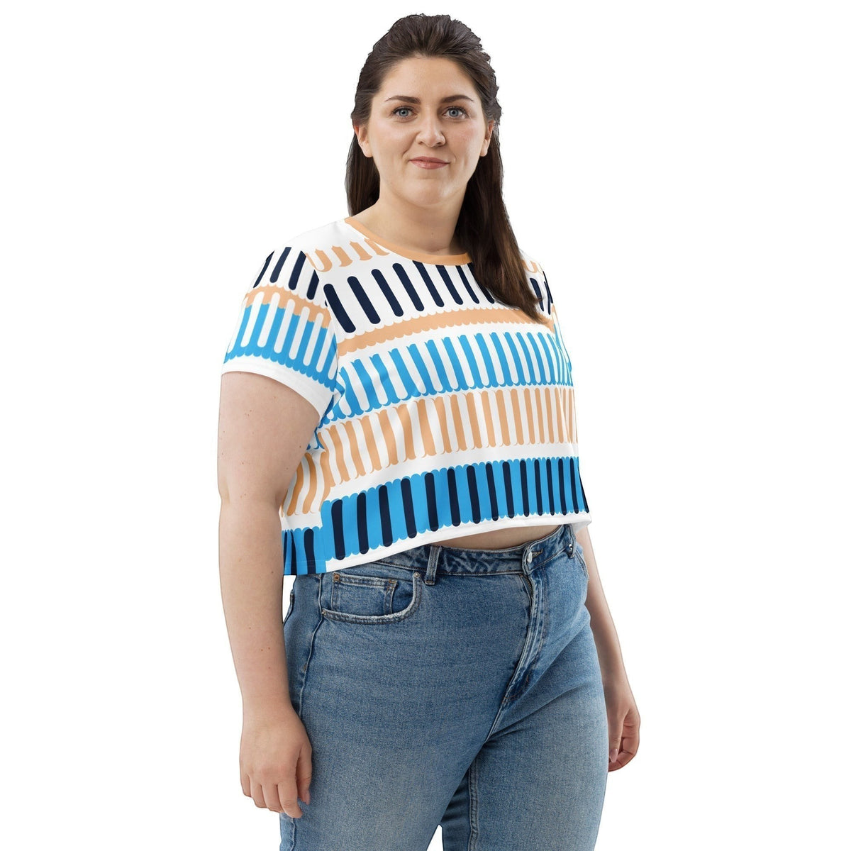 A woman wearing a Good Wishes 365 crop tee with a blue, orange, and white coastal rhythm pattern and jeans.