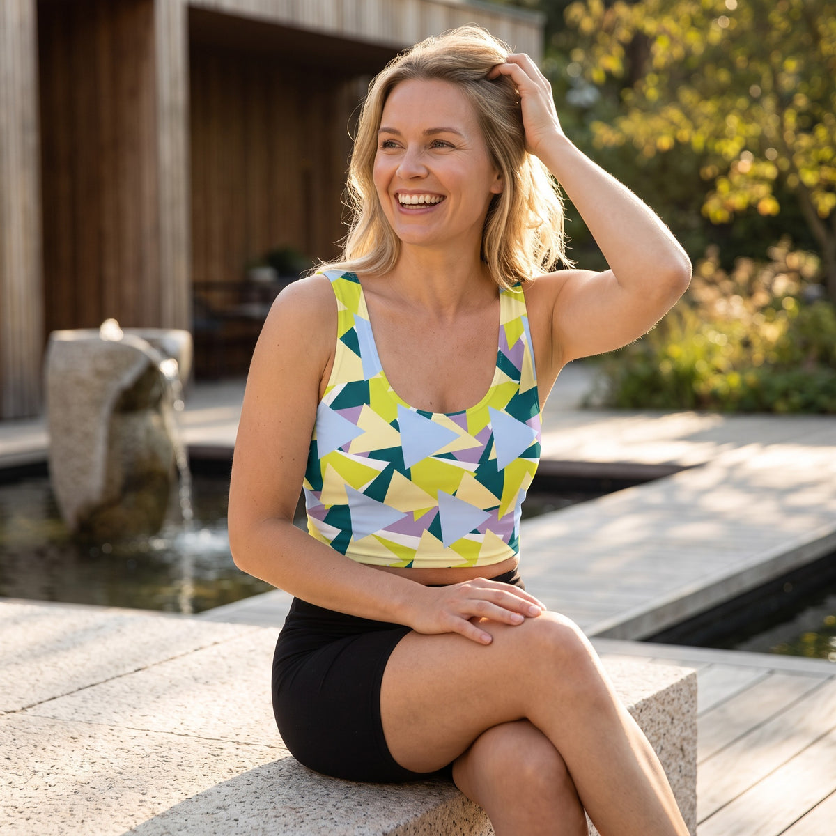 Good Wishes 365 sleeveless crop top with lime, blue, and lavender geometric triangle print worn by a smiling woman.