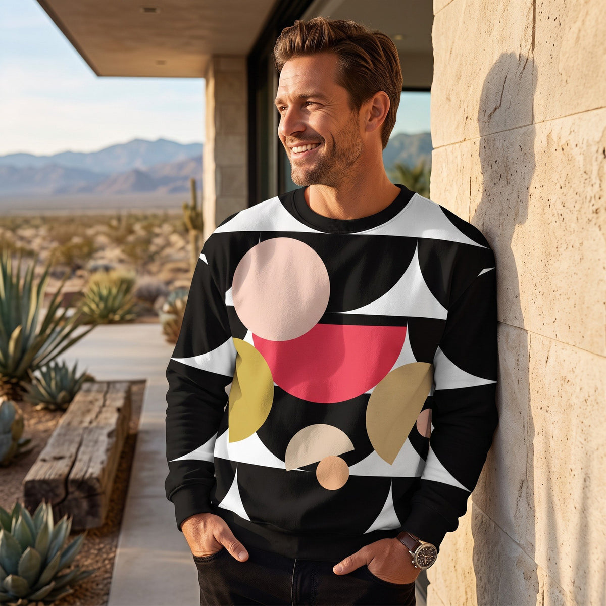 A man wearing a Good Wishes 365 black recycled sweatshirt with a geometric mushroom graphic in a desert setting.