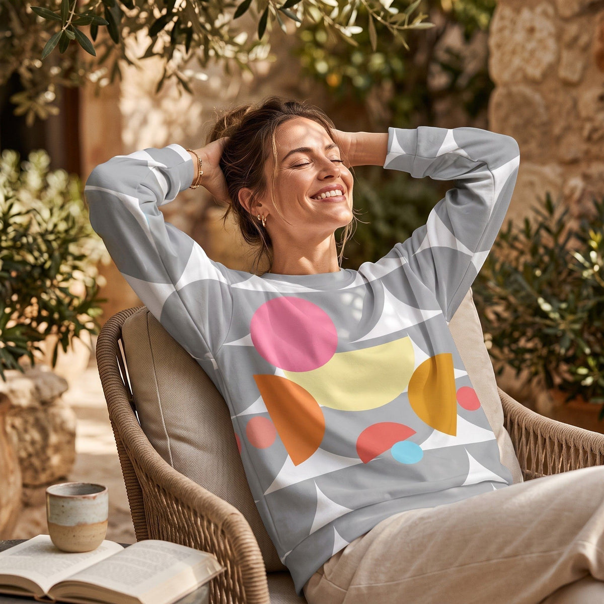 Good Wishes 365 recycled sweatshirt with silver geometric mushroom print worn by a smiling woman sitting outdoors.