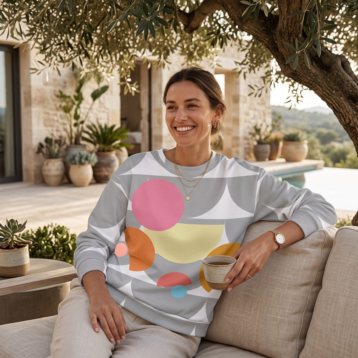 Good Wishes 365 recycled sweatshirt with silver geometric mushroom print worn by a smiling woman on a patio sofa.