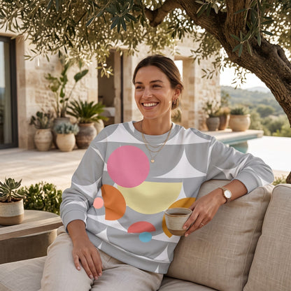 Good Wishes 365 recycled sweatshirt with silver geometric mushroom print worn by a smiling woman on a patio sofa.