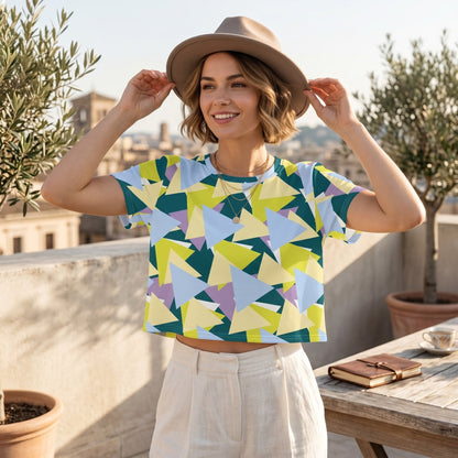 Good Wishes 365 woman wearing a colourful geometric print crop tee and a beige fedora hat on a sunny rooftop terrace.