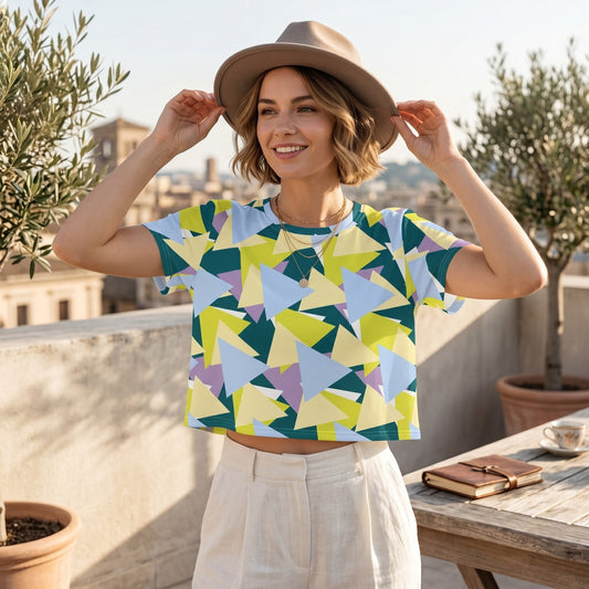 Good Wishes 365 woman wearing a colourful geometric print crop tee and a beige fedora hat on a sunny rooftop terrace.