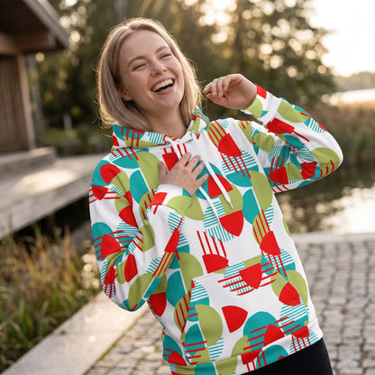 Good Wishes 365 recycled hoodie with a vibrant red, green, and teal geometric print worn by a smiling woman outdoors.