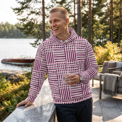 A man wearing a Good Wishes 365 recycled hoodie with a purple and blue geometric stripe pattern by a lakeside.