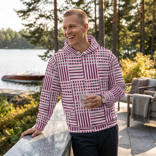 A man wearing a Good Wishes 365 recycled hoodie with a purple and blue geometric stripe pattern by a lakeside.