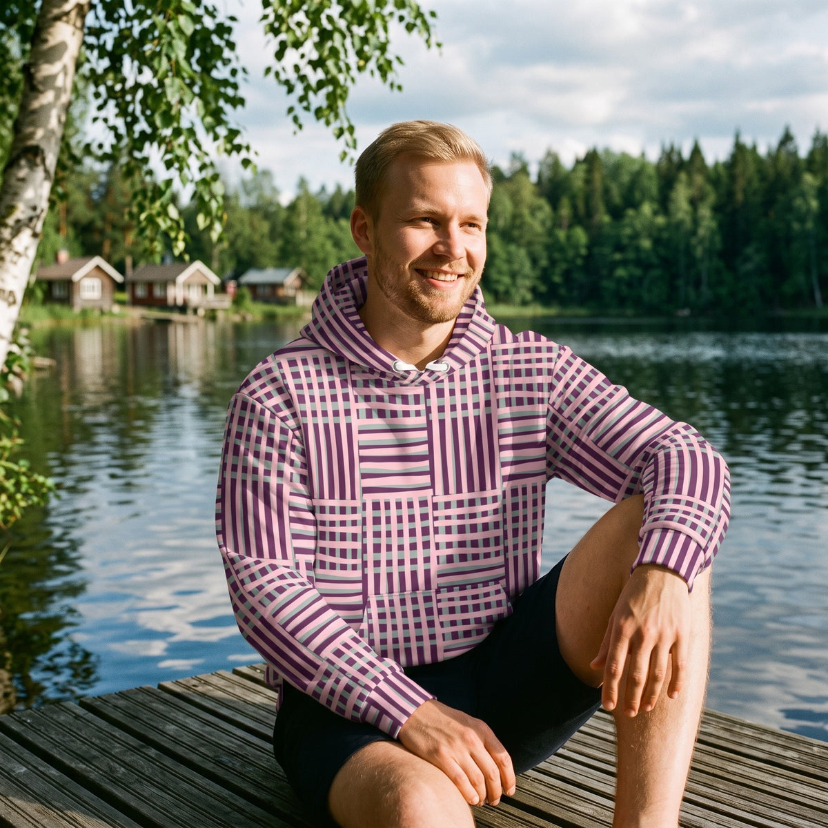 Good Wishes 365 recycled hoodie with purple and blue geometric stripes worn by a man sitting on a wooden lake dock