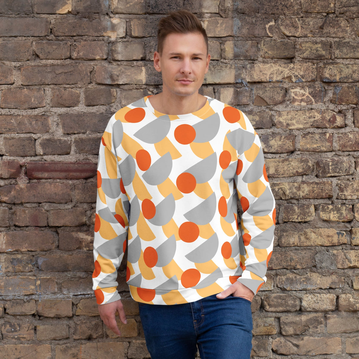 Good Wishes 365 men's recycled sweatshirt with orange, yellow, and grey geometric print against a brick wall background