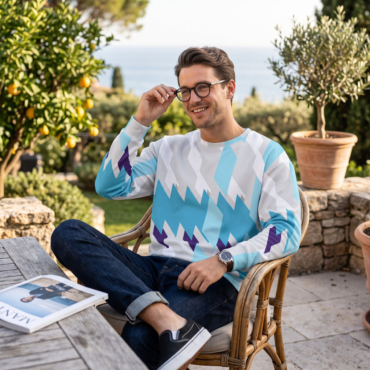 Good Wishes 365 unisex sweatshirt with blue and purple geometric print worn by a man sitting in a garden chair.