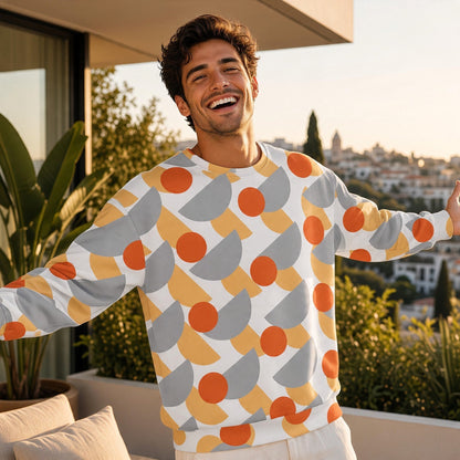 Good Wishes 365 recycled sweatshirt with orange, yellow, and grey geometric print worn by a smiling man on a balcony.