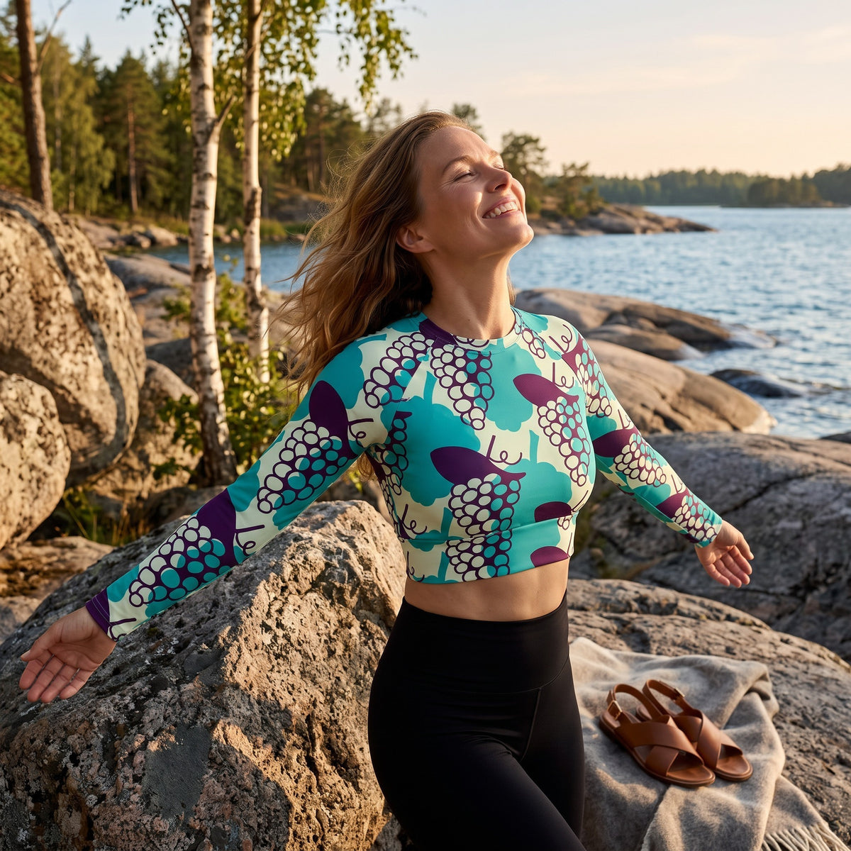 Good Wishes 365 long-sleeve crop top with grape print, featuring UPF 50+ recycled fabric, worn by a woman outdoors.