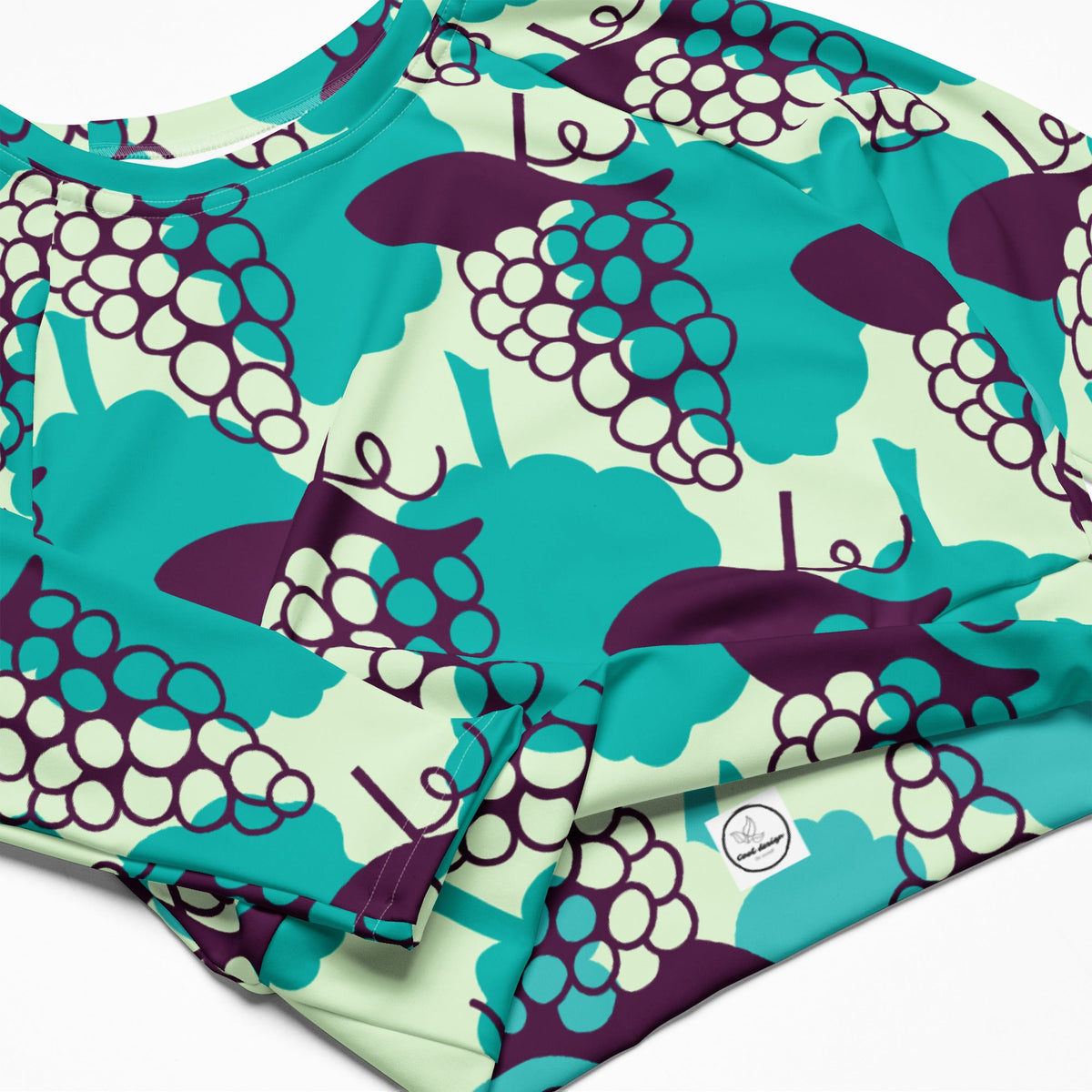 Good Wishes 365 long-sleeve crop top in recycled fabric with a vibrant purple and teal grape pattern and UPF 50+.