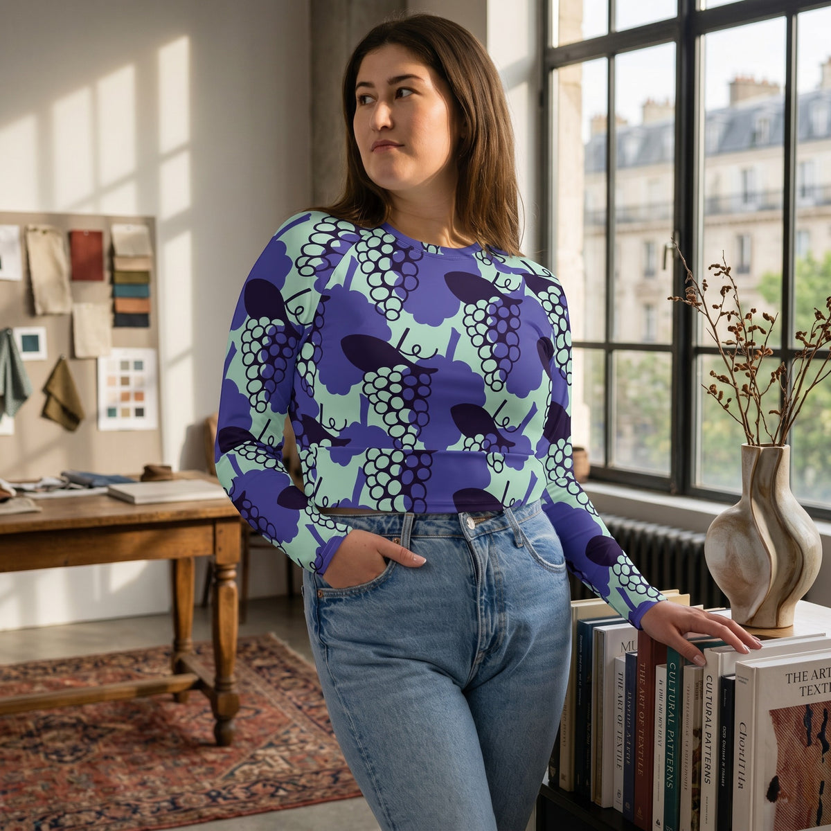 Good Wishes 365 long-sleeve crop top with purple and mint grape print, worn by a woman in a bright studio setting.