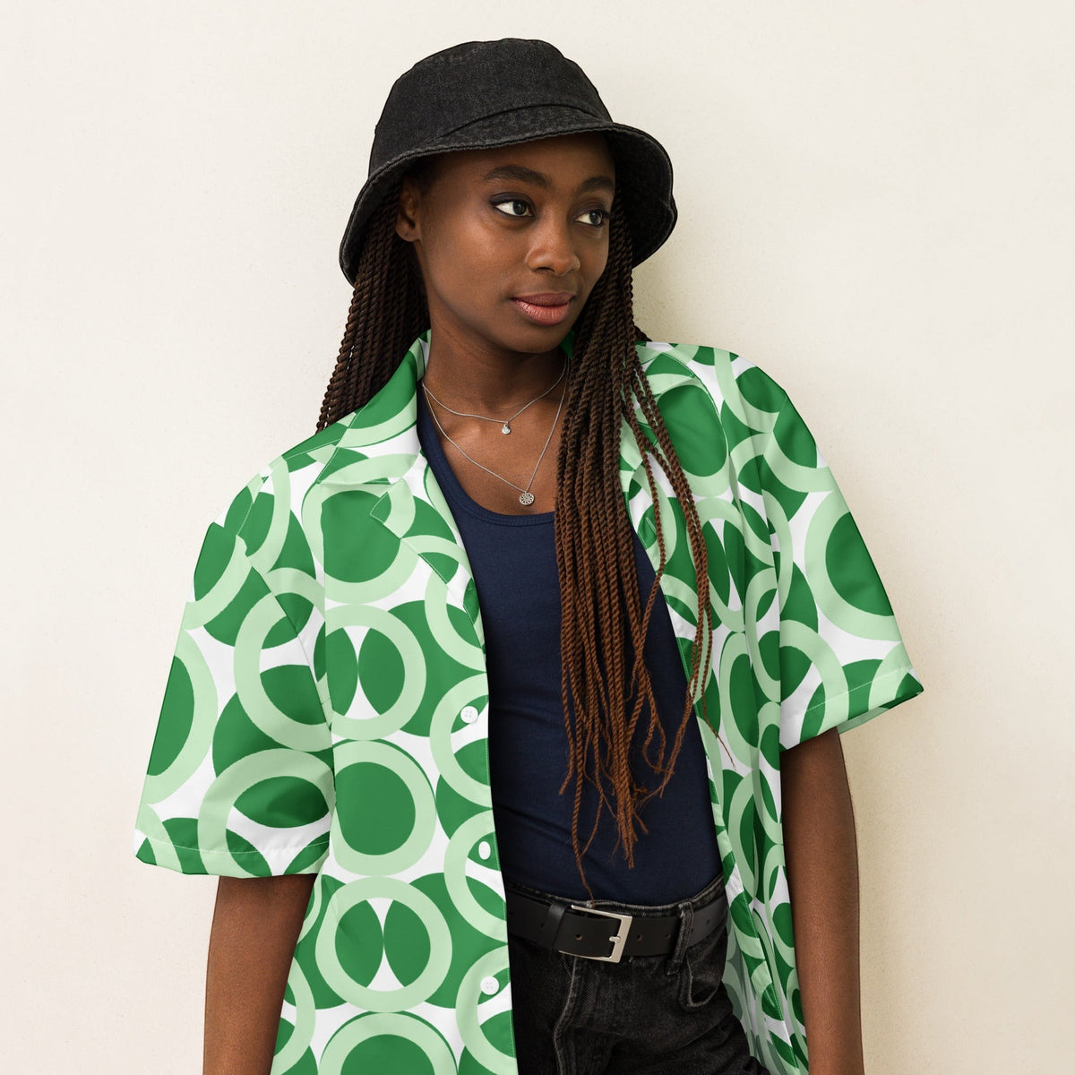 Good Wishes 365 unisex short sleeve button shirt in green with a retro geometric circle pattern worn over a dark top.