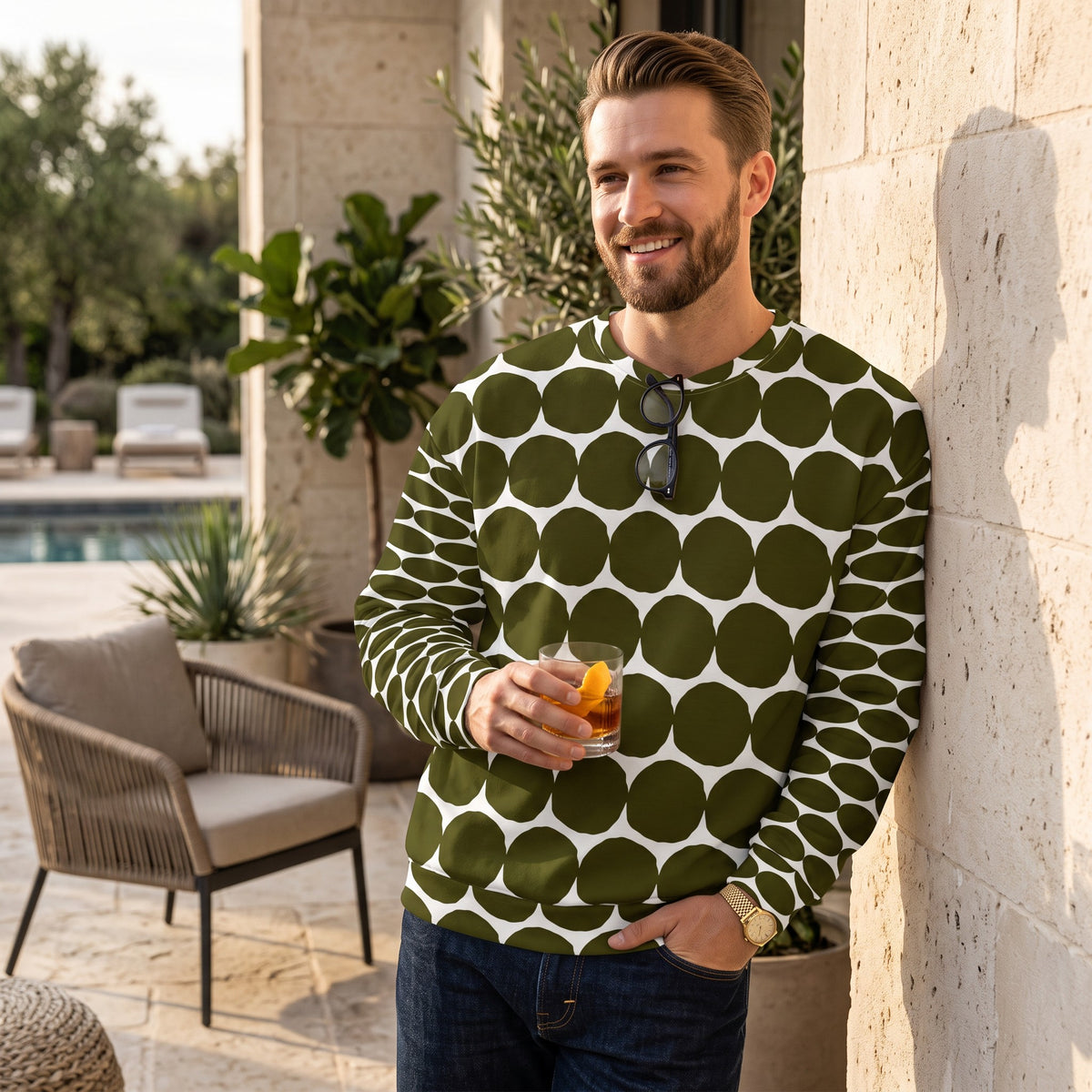 Good Wishes 365 unisex recycled sweatshirt in green and white pebble dot print worn by a smiling man on a patio.