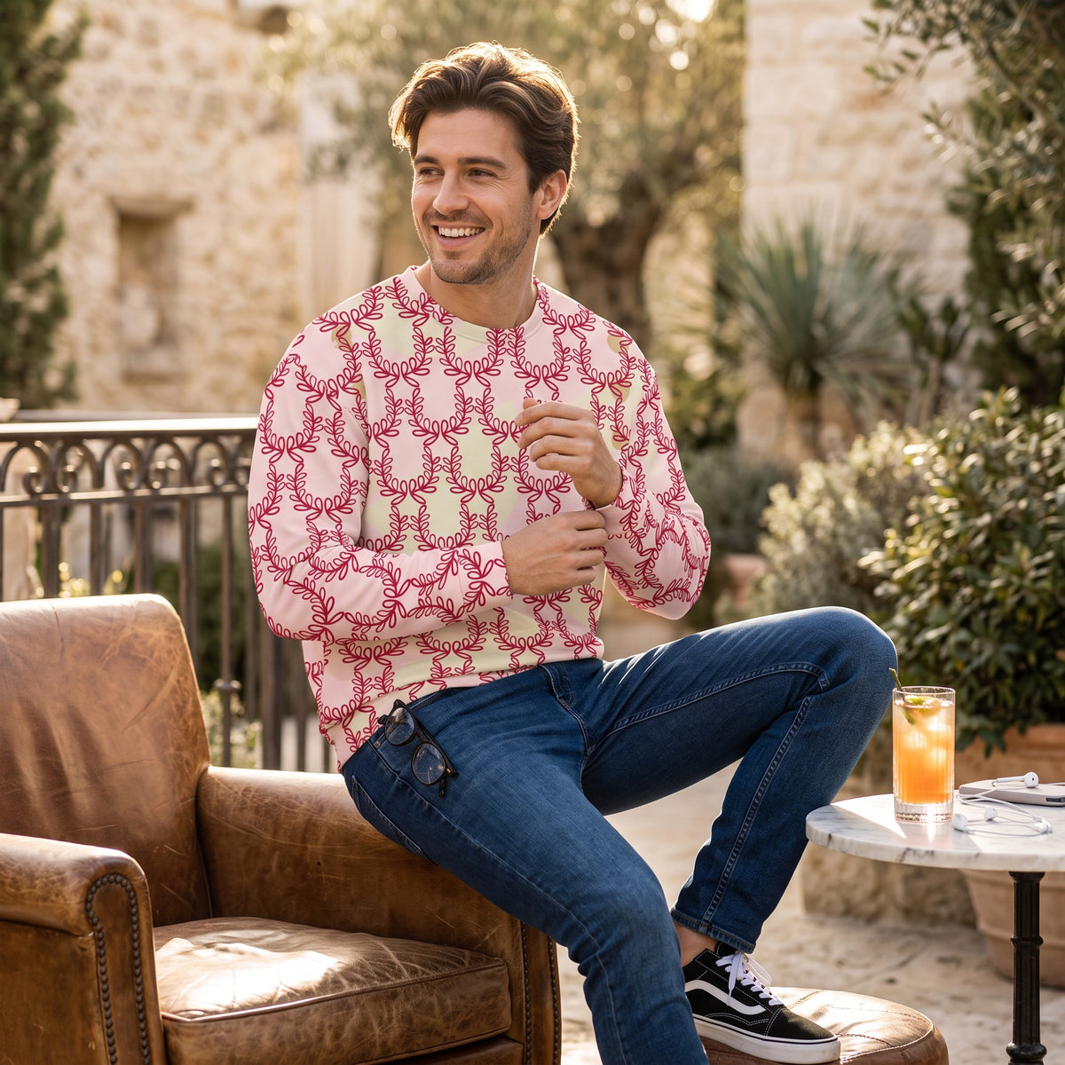 Good Wishes 365 unisex sweatshirt in misty rose with deep red laurel leaf crown print worn by a smiling man outdoors.