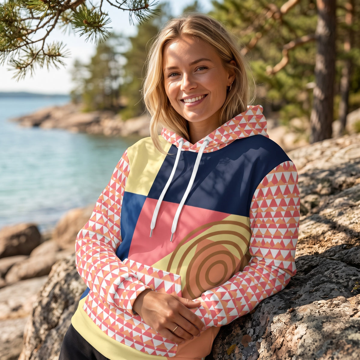 Good Wishes 365 recycled hoodie with 80s Memphis geometric print in navy, yellow, and coral worn by a smiling woman.
