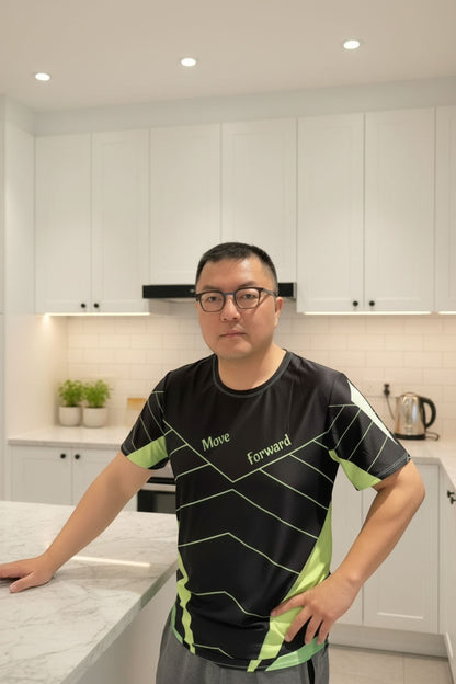 Good Wishes 365 men's black and neon green athletic training shirt with V-line graphic worn by a man in a kitchen.