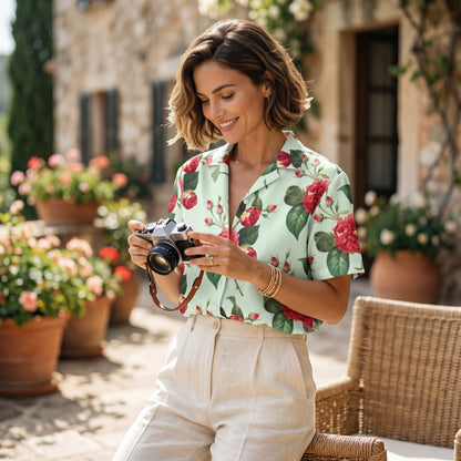 A woman wearing a Good Wishes 365 mint green short-sleeve button shirt with a red rose floral print outdoors.