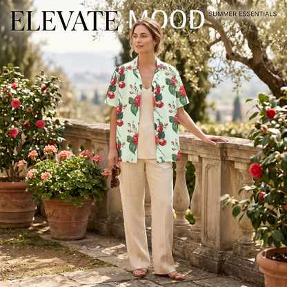 Good Wishes 365 mint green short sleeve button shirt with red rose floral print worn by a woman in a garden setting.